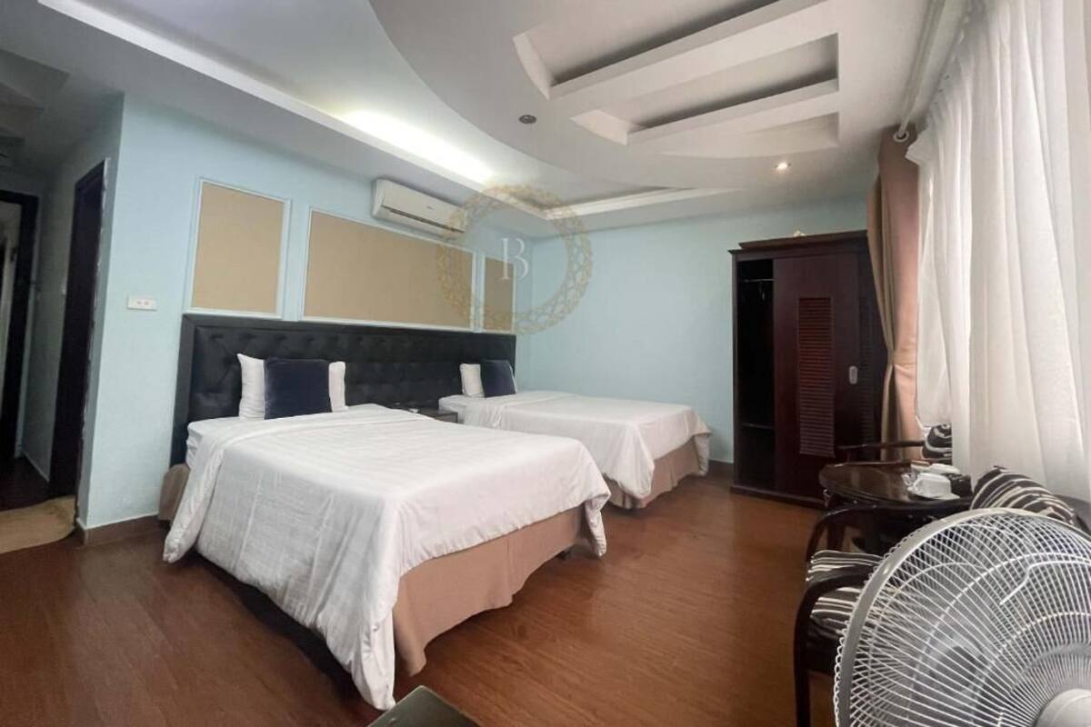 A hotel room with two beds, a ceiling fan, and a wooden floor.