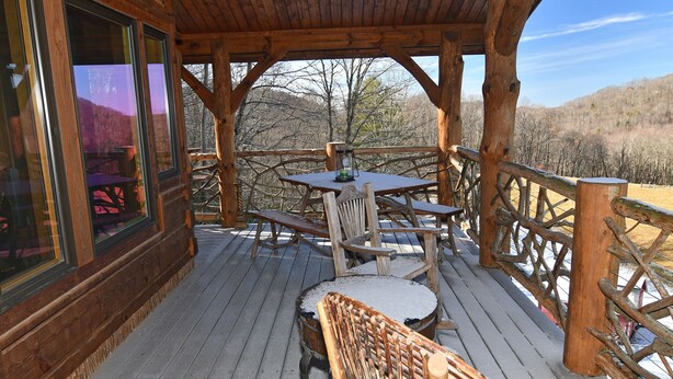 Eine Holzterrasse mit Tisch und Stühlen mit Blick auf eine Berglandschaft.