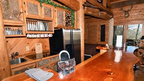 Ein Holzhütten-Innenraum mit Küchenbereich, einschließlich eines Edelstahl-Kühlschranks, Holzschränken und einer Theke.