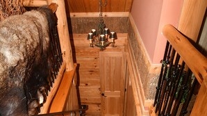 Eine Holztreppe führt zu einem Zimmer mit einem Bett und einer Chandelüster.