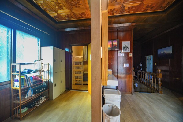 A room with wooden flooring, a built-in bookshelf, a white refrigerator, and a staircase with a wooden railing. - Seoul Papa Guesthouse (Seoul)