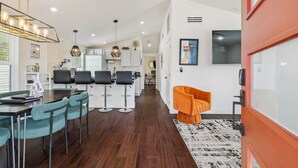 A modern kitchen with white cabinets, a dining area with teal chairs, and a bar area with black stools. - Downtown Phoenix Modern Retreat | 2 Homes in 1! (Phoenix)
