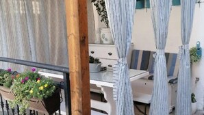 A covered outdoor seating area with striped curtains, a white table, and planters with flowers. - Apartment AD - Pirovac (Pirovac)