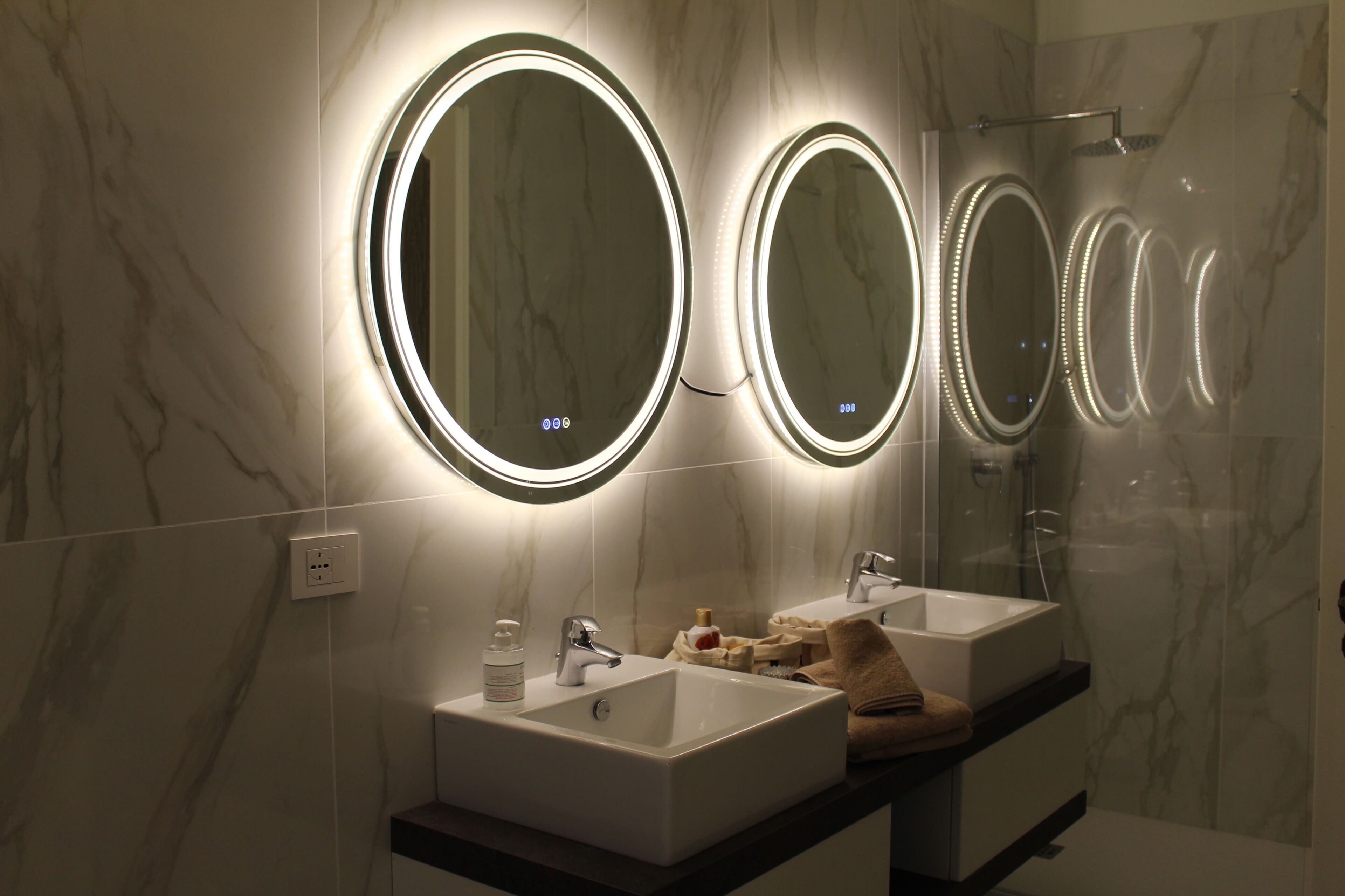 A bathroom with three round mirrors, a sink, and a shower.