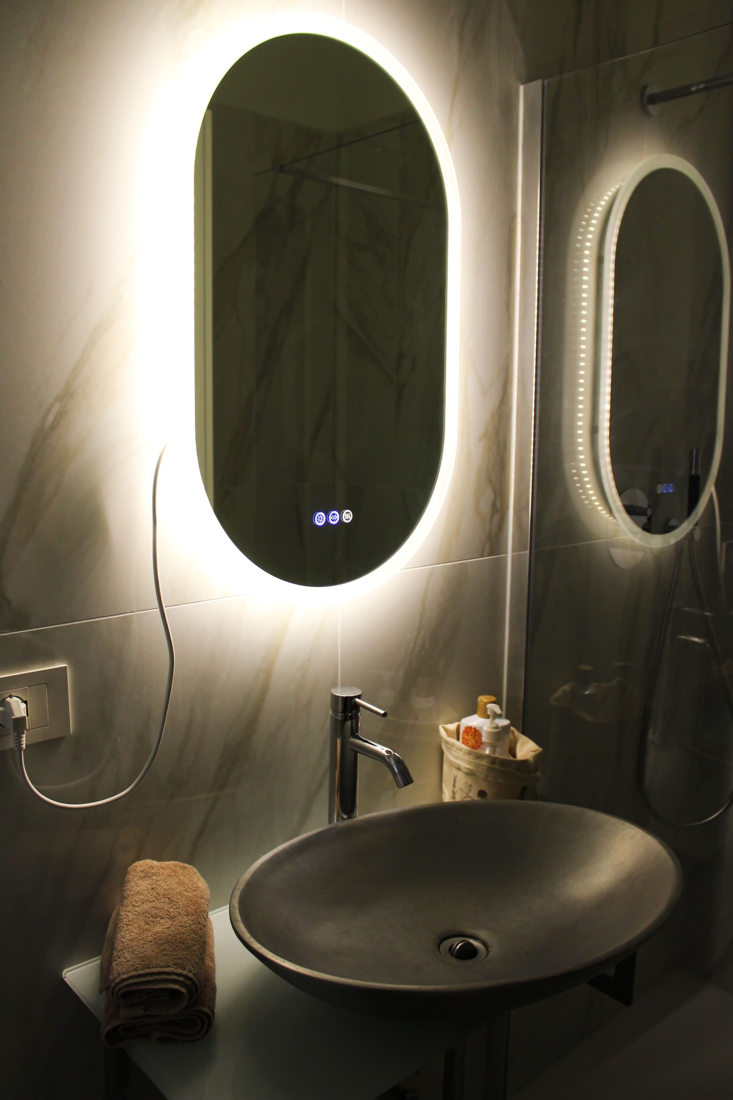 A bathroom with a round mirror, a sink, and a towel.