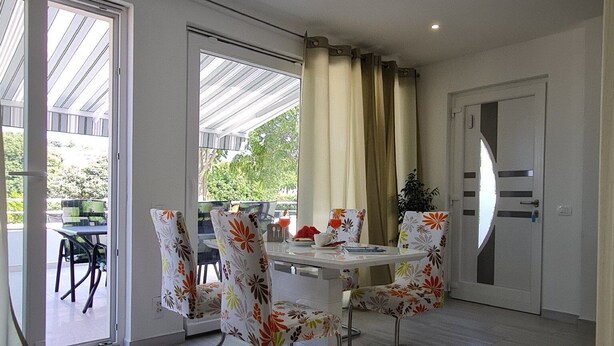A dining area with a table and chairs, a ceiling light, and a door. - Luxury Apartment Ani II (Sutivan)