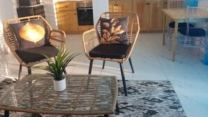 Un salon moderne avec des fauteuils en osier, une table basse en verre et une plante en pot.