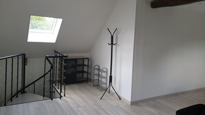 A spacious loft with a high ceiling, a skylight, a staircase, and a metal coat rack. - La Casa d'Augy à Farges, proche de Avord et Bourges en gite de 2 à 8 personnes (Farges-en-Septaine)