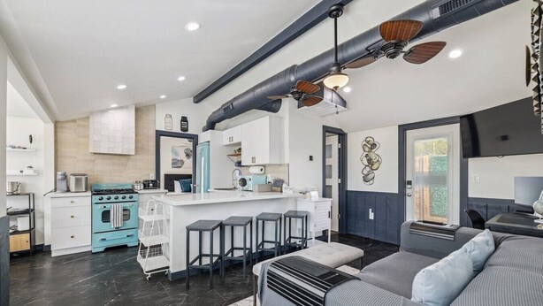 A modern kitchen with a central island, bar stools, and a dining area with a sofa. - The Garfield Hideaway| 2BR/2BA | Walk to Downtown (Phoenix)