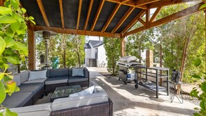 An outdoor patio with a covered seating area, a grill, and a trash bin. - The Garfield Hideaway| 2BR/2BA | Walk to Downtown (Phoenix)