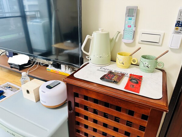 A hotel room with a wooden desk, a television, a kettle, a mug, and a wall-mounted control panel. - Hsinchu Peace (Zhubei)