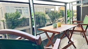 A balcony with a wooden table and chairs, a green bag, and two mugs. - Hsinchu Peace (Zhubei)