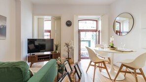 Relax in this stylish living space with a flat-screen TV, green sofa, and dining area for two.