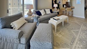 A modern living room with a grey sofa set, a white coffee table, and a patterned rug.