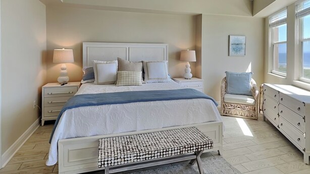 A bedroom with a bed, bedside tables, a chair, a dresser, a ceiling fan, and a window.
