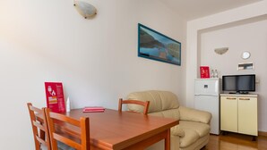 A compact living space with a wooden dining table, beige sofa, and a small kitchenette. - Urban Cozy Apartment by Wonderful Italy (Bologna)