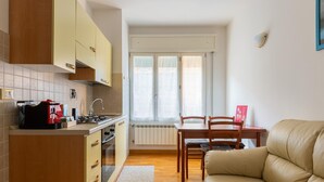 A compact kitchen with a dining area, a sofa, and a window with curtains. - Urban Cozy Apartment by Wonderful Italy (Bologna)