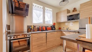 A modern kitchen with wooden cabinets, a built-in oven, a microwave, and a coffee maker. - House for 5 - 300m from Tanchet beach (Les Sables-d´Olonne)