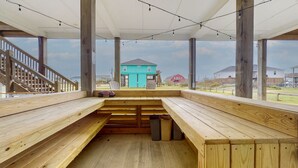 Ein überdachter Außenbereich mit Holzbanken und Blick auf Häuser im Hintergrund.