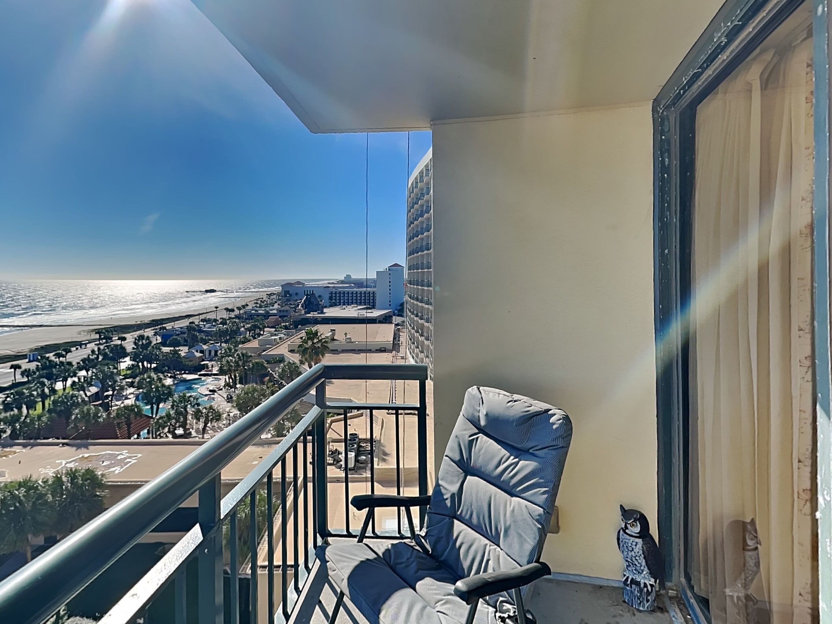 Un balcon donnant sur la plage, une chaise et une petite décoration en forme de hibou.
