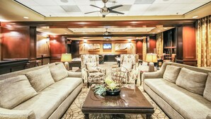 A hotel lobby with two sofas facing a television, a ceiling fan, and a reception desk. - San Luis Manor by Ryson Vacation Rentals (Galveston)