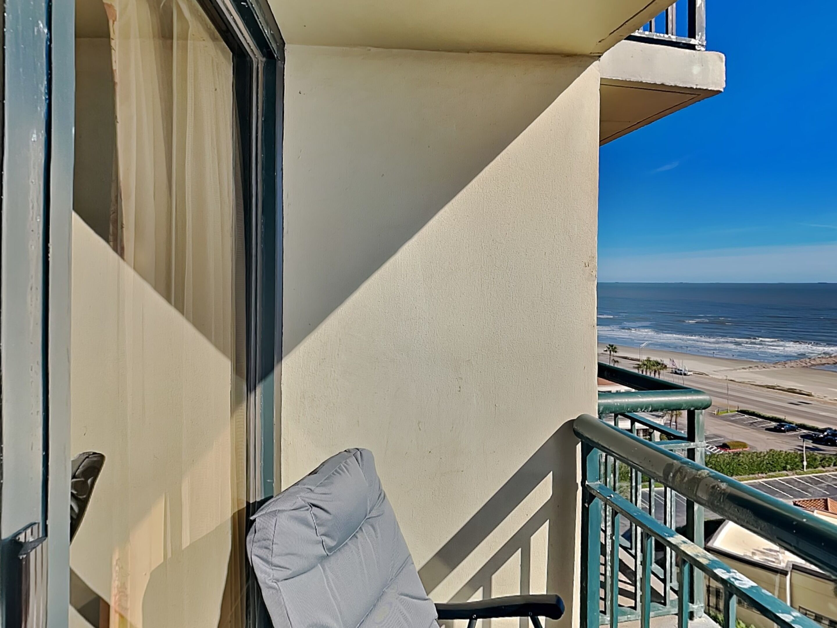A balcony with a view of the ocean and a chair.