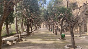 A pathway lined with trees and benches, leading towards a stone building. - Comfortable & spacious Villa close from Leana Thermes- Clim & Private pool-  (Fortuna)