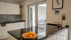 A modern kitchen with white cabinets, a black countertop, and a bowl of oranges. - NEU Luxuswohnung in Waldrandlage Nähe Köln Messe! (Leverkusen)