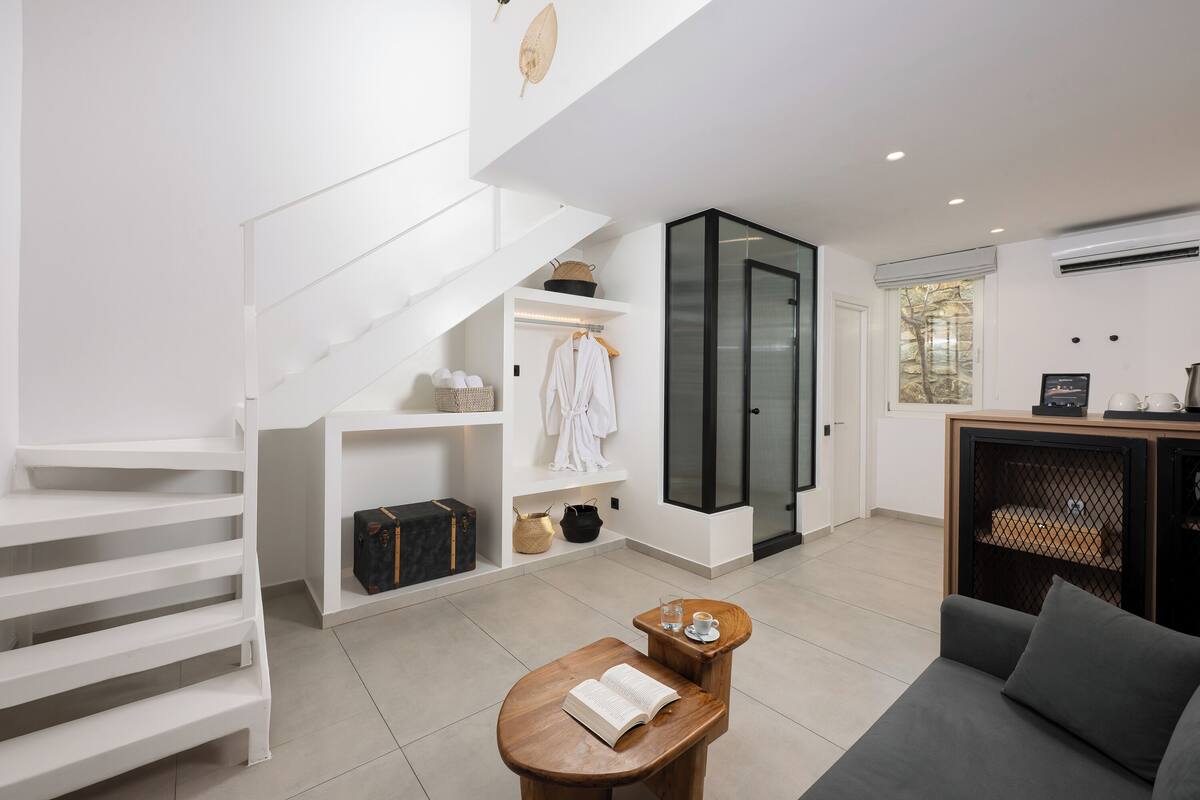 Ein modernes Interieur mit Treppe, Glastür, Sofa und einem kleinen Tisch mit einem Buch.