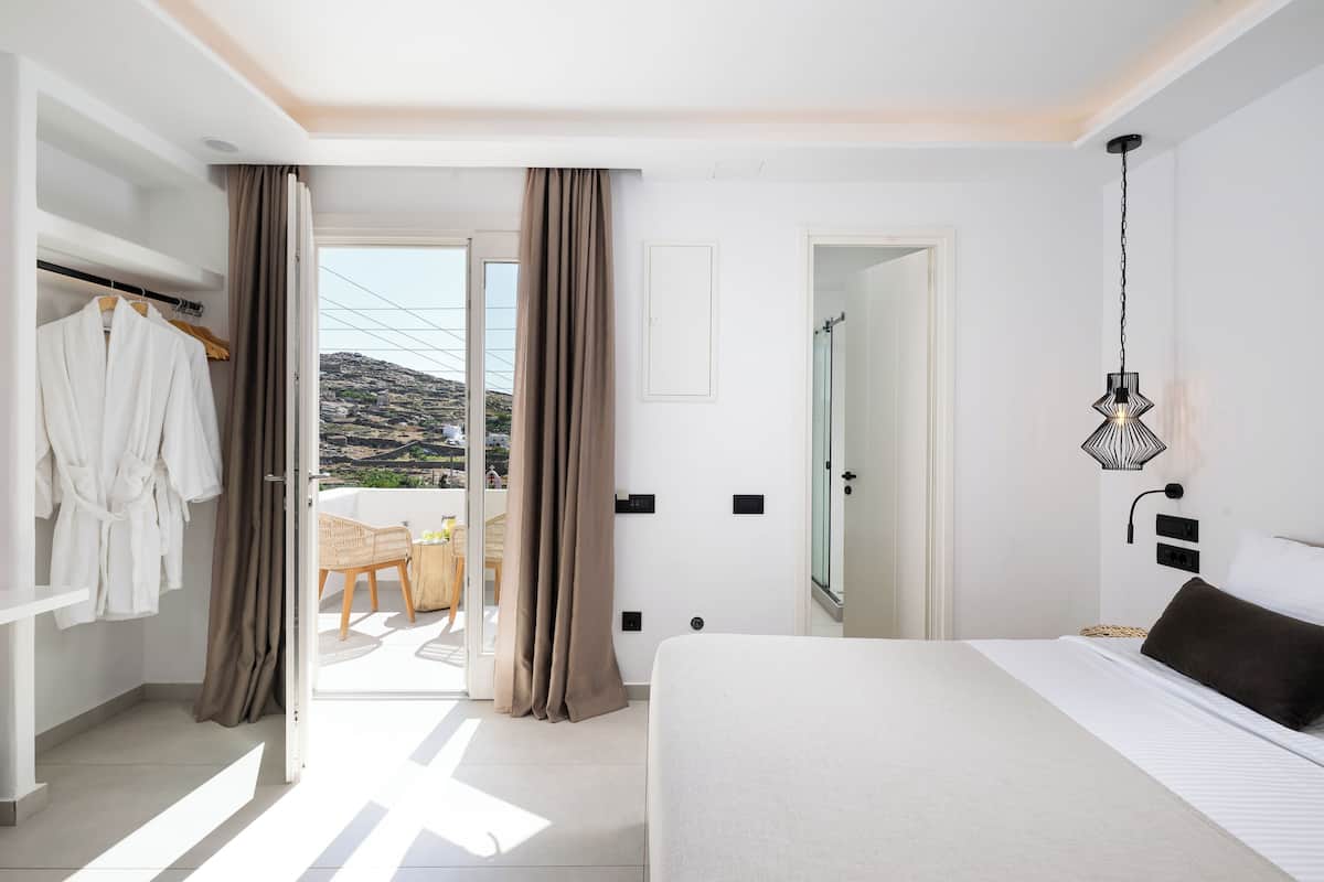 Ein Schlafzimmer mit Bett, Kleiderschrank, einer Pendelleuchte und Blick ins Freie.