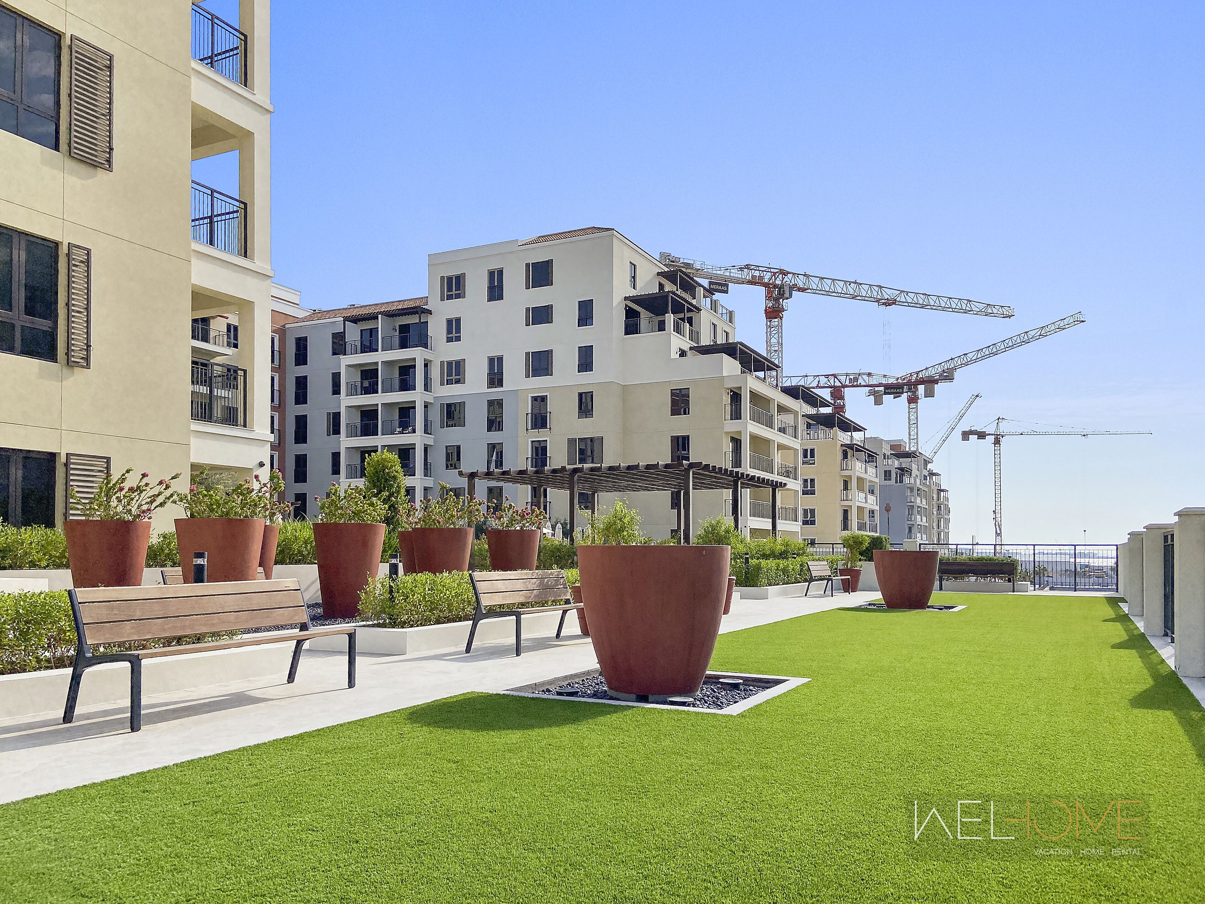 A modern building with multiple balconies and large potted plants.