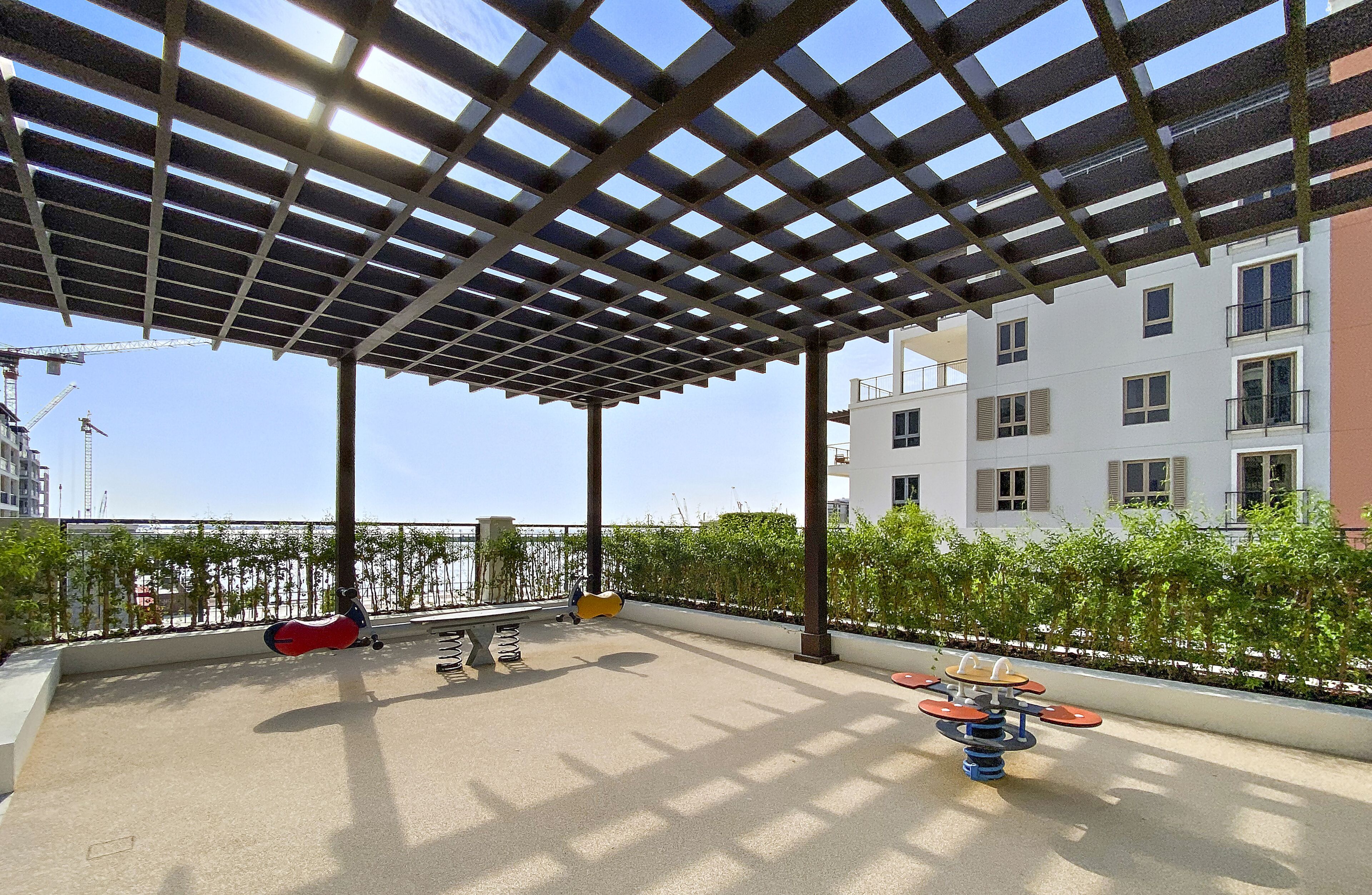 An outdoor patio with a pergola, seating, and exercise equipment.