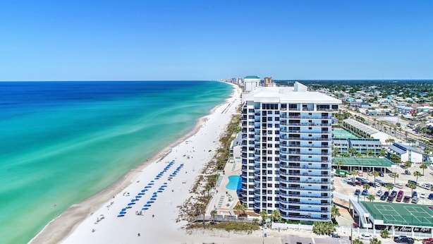 A beachfront hotel with a pool, beach umbrellas, and a view of the ocean.