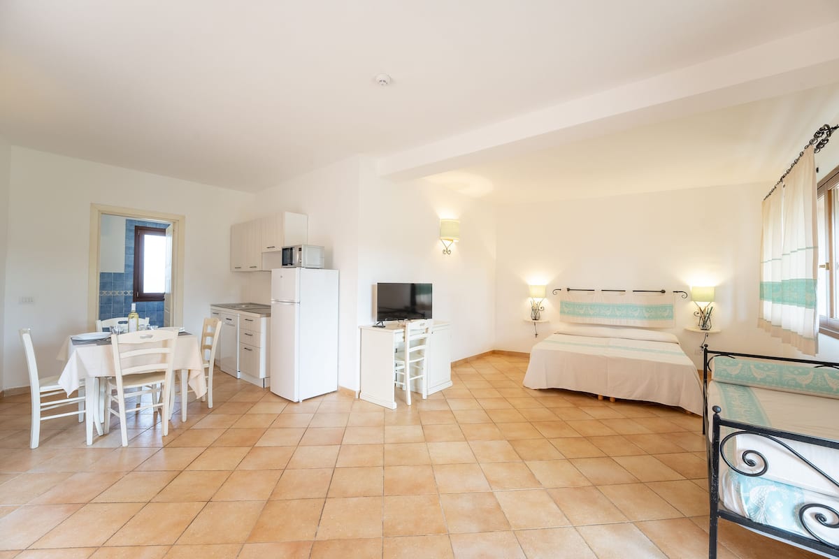 Un espacio habitable compacto con comedor, kitchenette y cama.