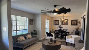 A modern living room with a gray sofa, a round coffee table, and a dining area with a table and chairs. - CENTRALLY LOCATED CLOSE TO AIRPORT & MCALLISTER PARK- 4 BR, 3.5 bath, 2800 SQ FT (San Antonio)