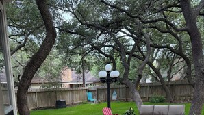 A backyard patio with stone flooring, a gray sofa, and red Adirondack chairs. - CENTRALLY LOCATED CLOSE TO AIRPORT & MCALLISTER PARK- 4 BR, 3.5 bath, 2800 SQ FT (San Antonio)