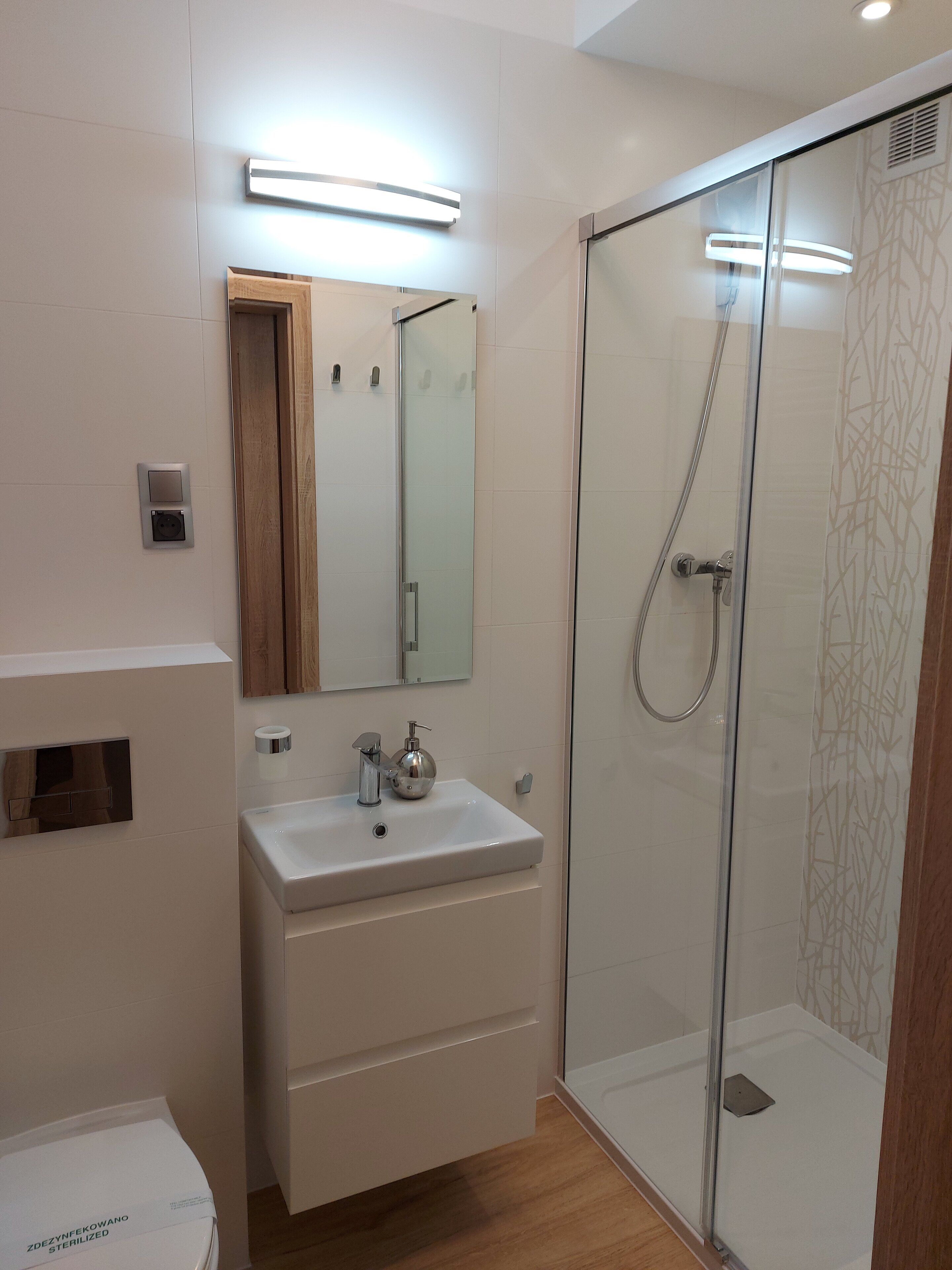 A modern bathroom with a glass-enclosed shower, a white sink, and a mirror above it.