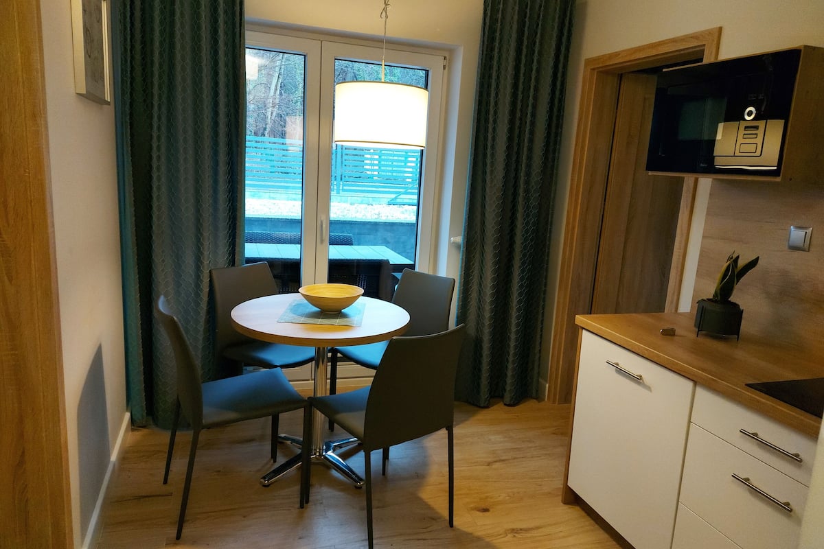 Une cuisine compacte avec un coin repas, comprenant une table ronde avec des chaises, un four à micro-ondes et un petit meuble de rangement.