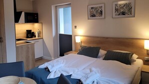 Een hotelkamer met een bed, een bureau met een magnetron, een koffiezetapparaat en twee ingelijste kunstwerken aan de muur.