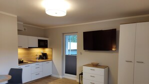 Een kleine keuken met een magnetron, koffiezetapparaat en een eethoek met een tafel en stoelen.