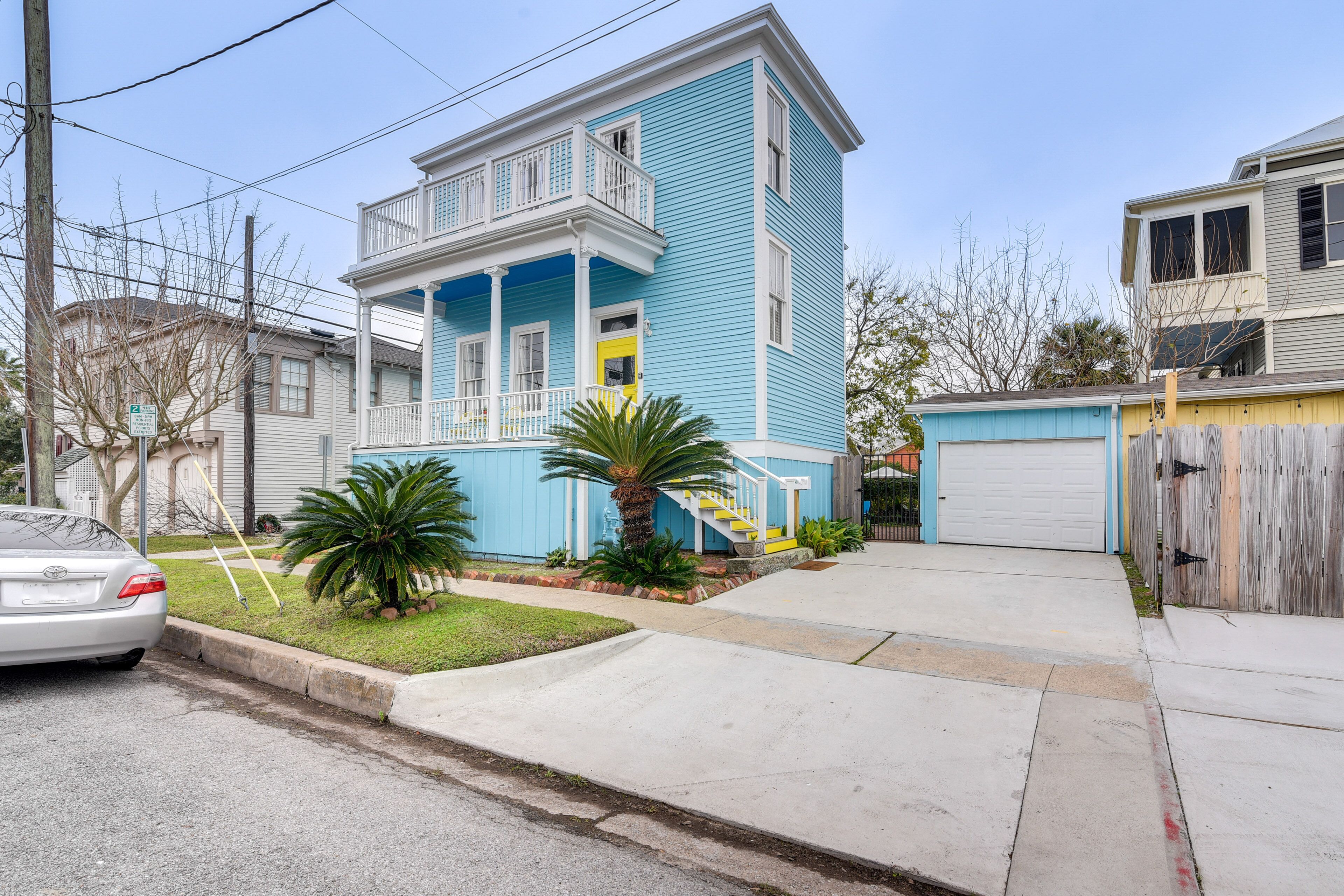 A two-story house with a blue exterior, a front porch, and a yellow door.