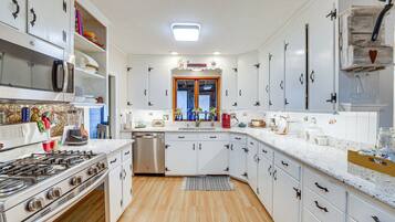Une cuisine moderne avec des armoires blanches, des appareils en acier inoxydable et un plancher en bois.