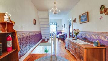 Un couloir avec un escalier, des meubles en bois, un lustre et des décorations murales représentant des papillons.