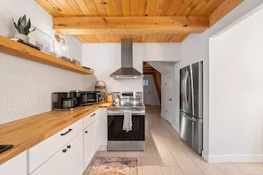 Una cocina moderna con vigas de madera, electrodomésticos de acero inoxidable y un tapete estampado.