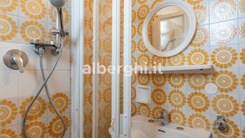 Un baño con ducha, lavabo y espejo.