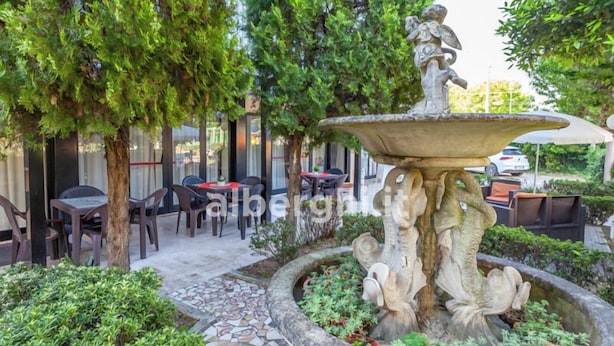Un espace extérieur aménagé avec une fontaine en pierre, des tables et des chaises.