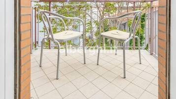 A balcony with two metal chairs and a tiled floor.