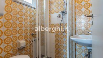 A bathroom with a shower, toilet, and sink, featuring a patterned tile design.