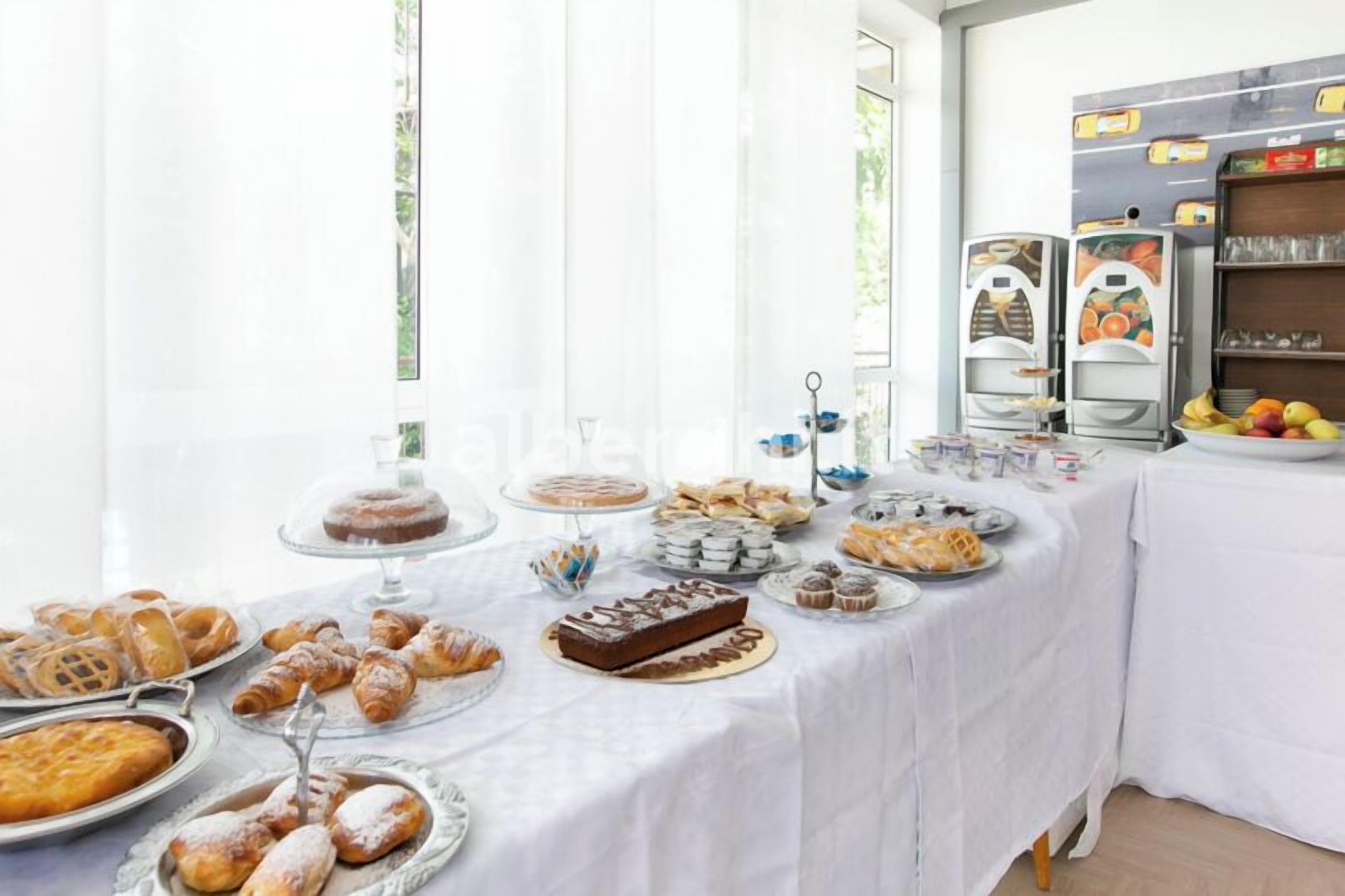 A buffet table with various baked goods and pastries, including croissants, muffins, and a cake.