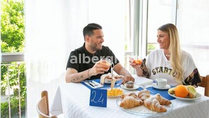 Deux personnes sont assises à une table, devant un petit-déjeuner composé de croissants, de jus d’orange et de café.